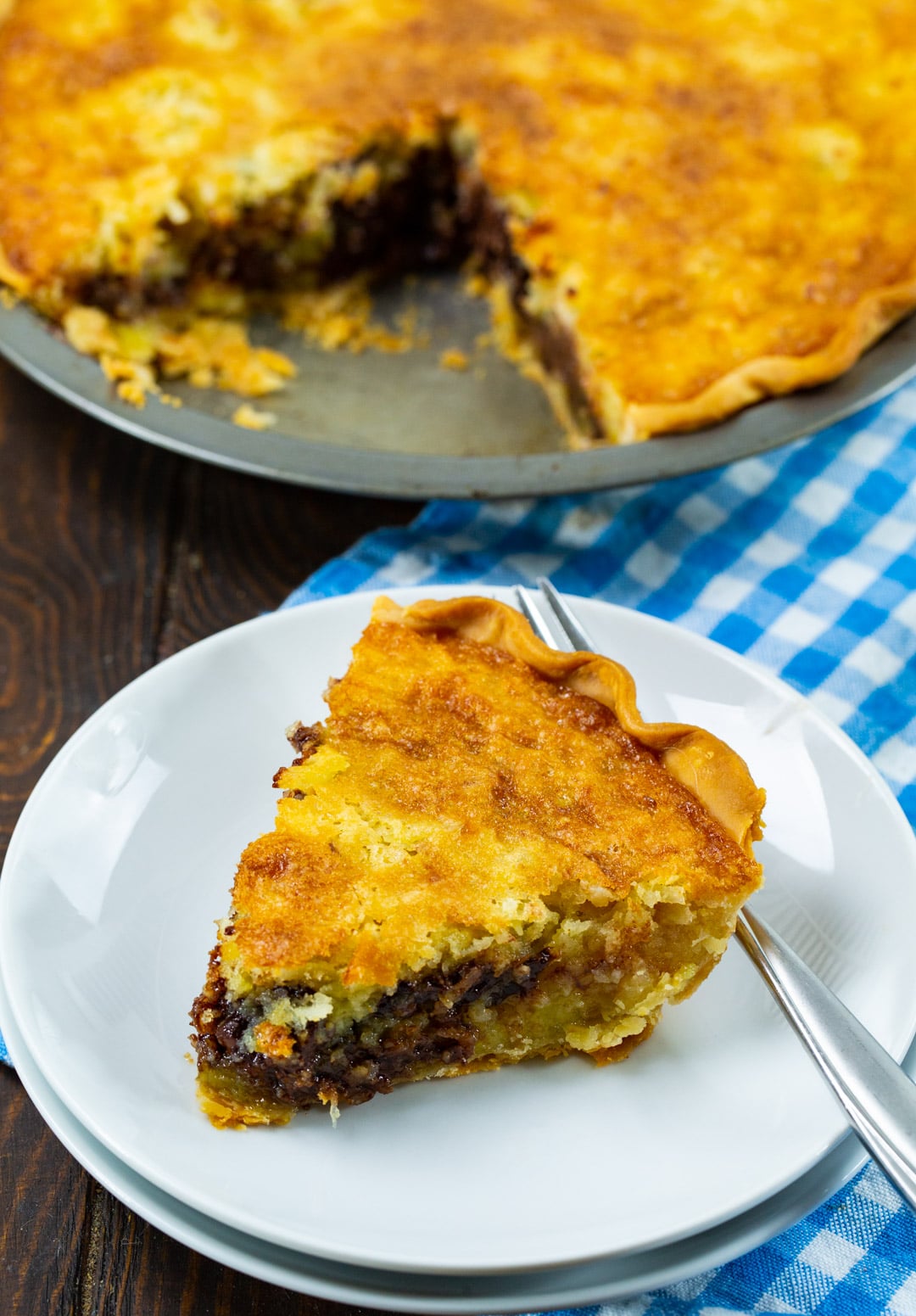 Slice of pie on a plate with rest of pie in background.