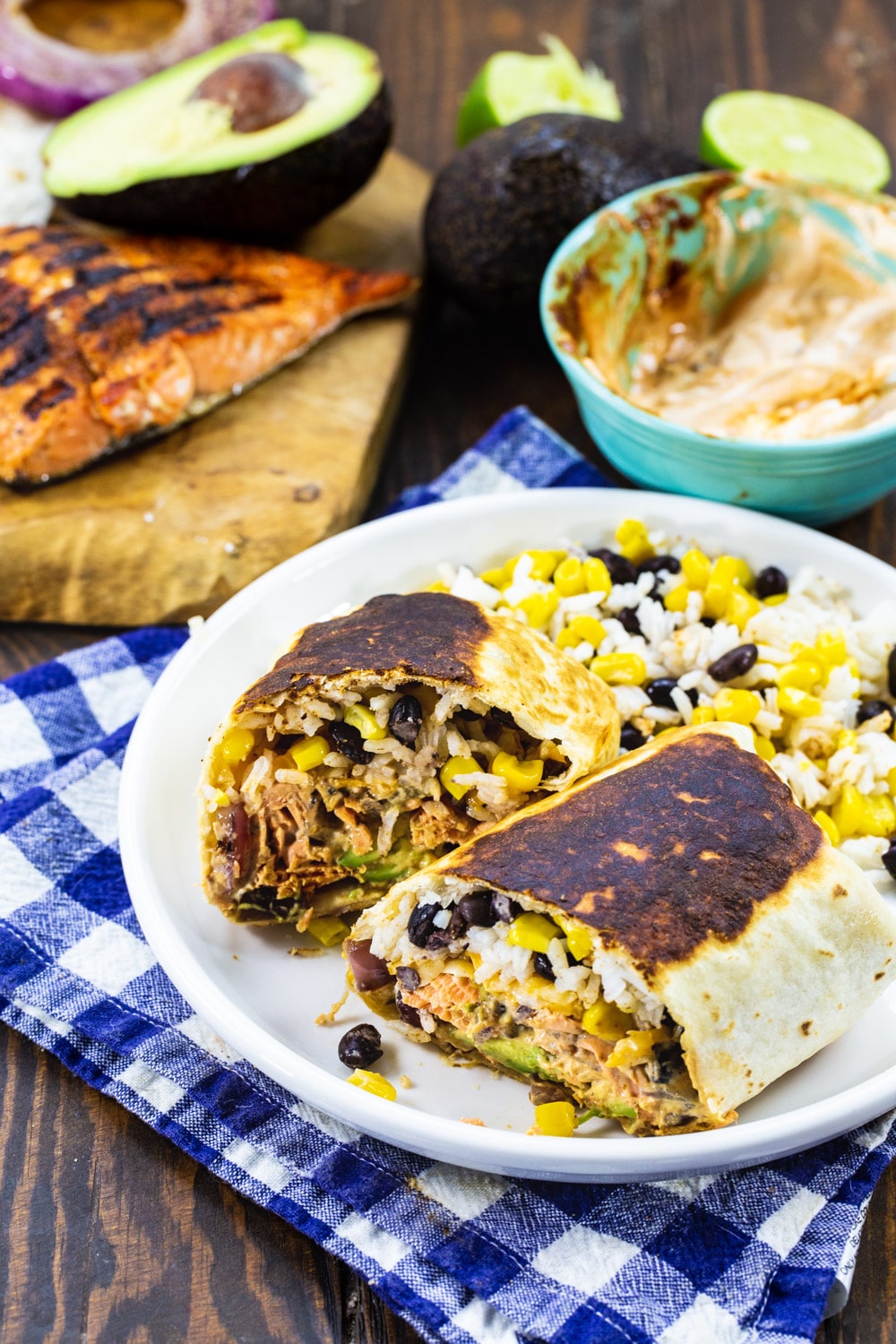 Salmon Burrito cut in half on a plate with rice.