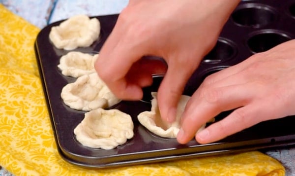 Pressing biscuits into muffin cups.