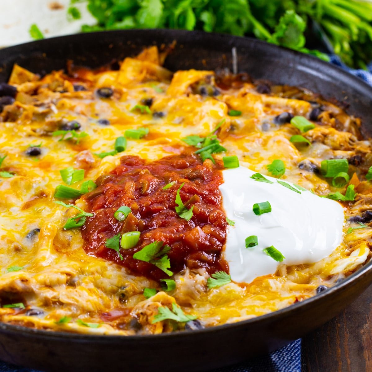 Chipotle Chicken Enchilada Skillet topped with sour cream and salsa in a skillet.