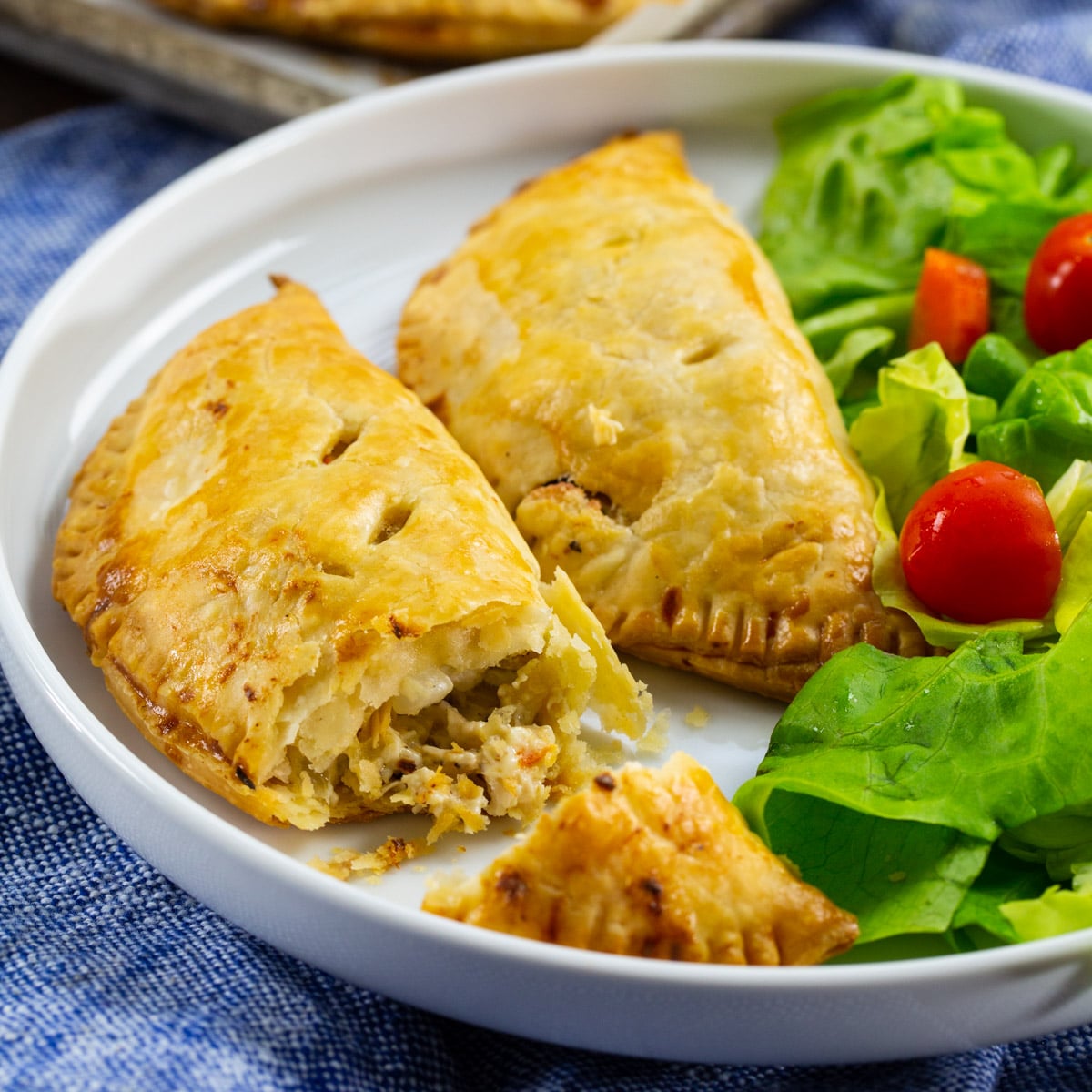 Two Creamy Chicken Hand Pies on plate with salad.