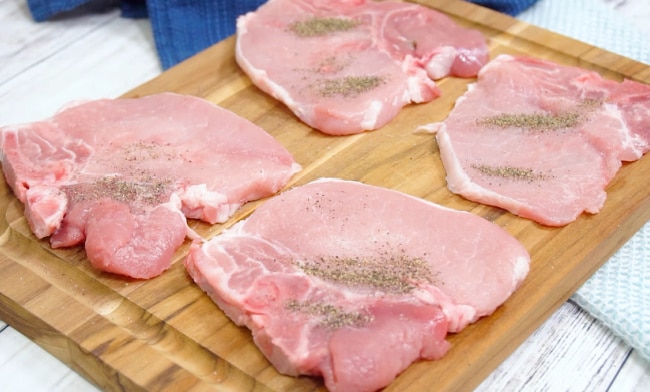 Seasoning the pork chops.