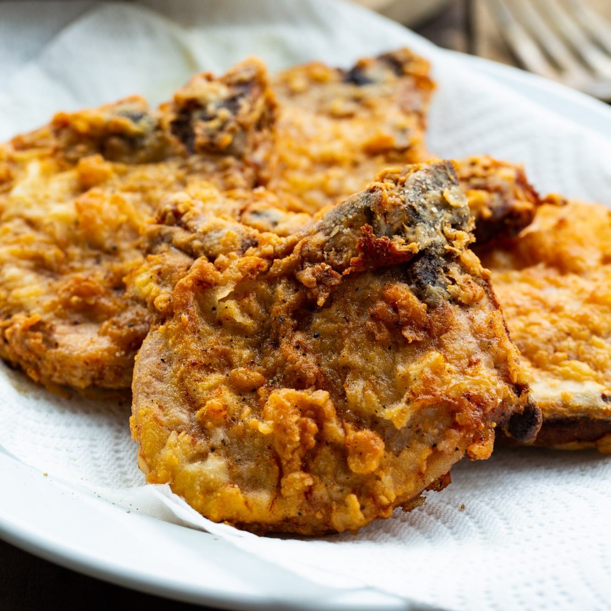 Southern Fried Pork Chops on a paper-towel-lined plate.