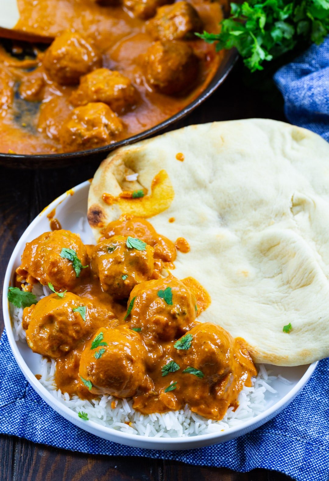 Butter Chicken Meatballs on a plate with naan and skillet full of meatballs.
