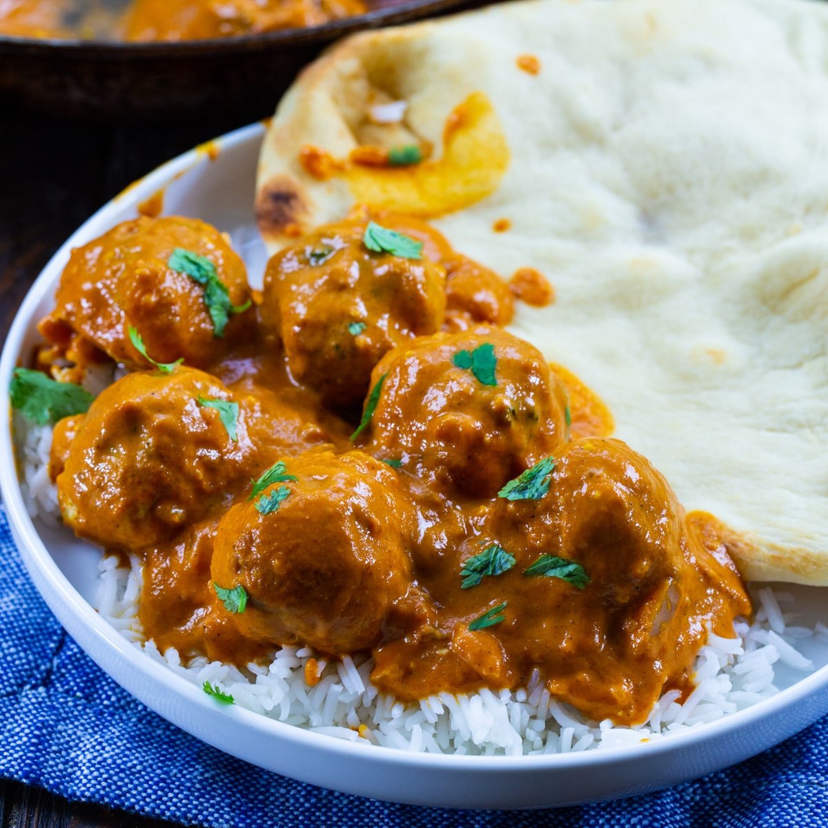 Butter Chicken Meatballs over rice on a plate.