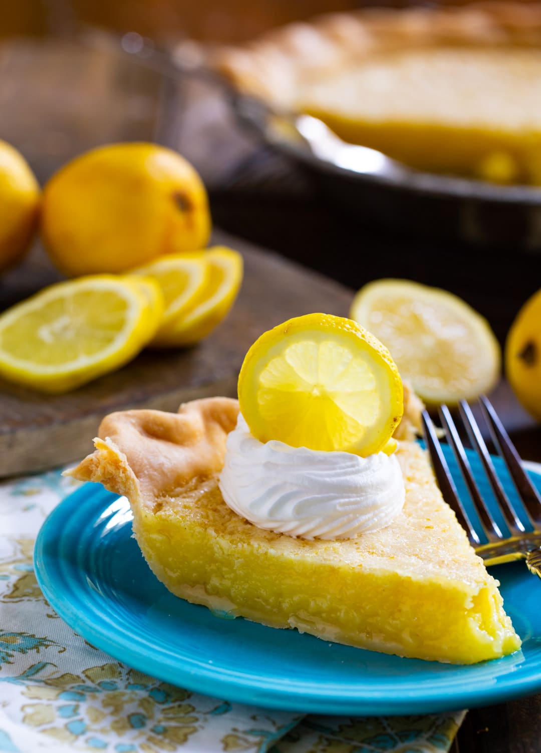 Slice of pie on plate with lemons in background.