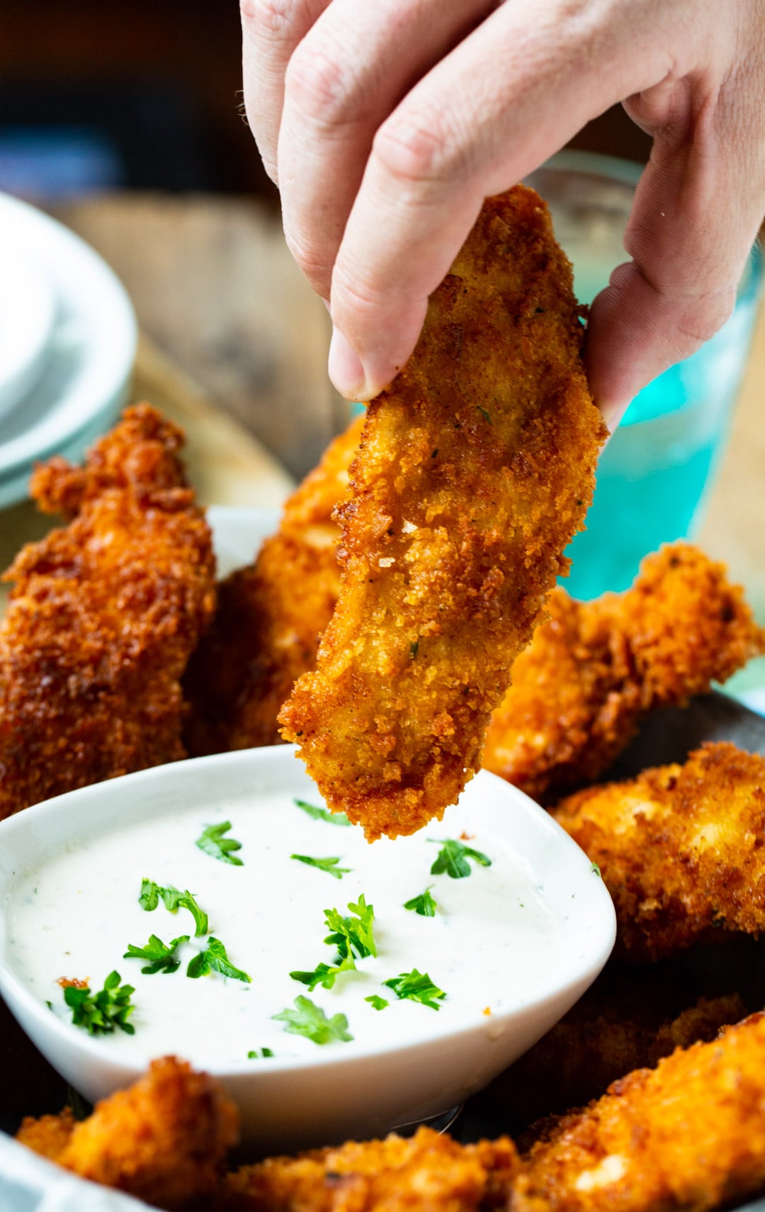CHicken finger getting dipped in ranch dressing.