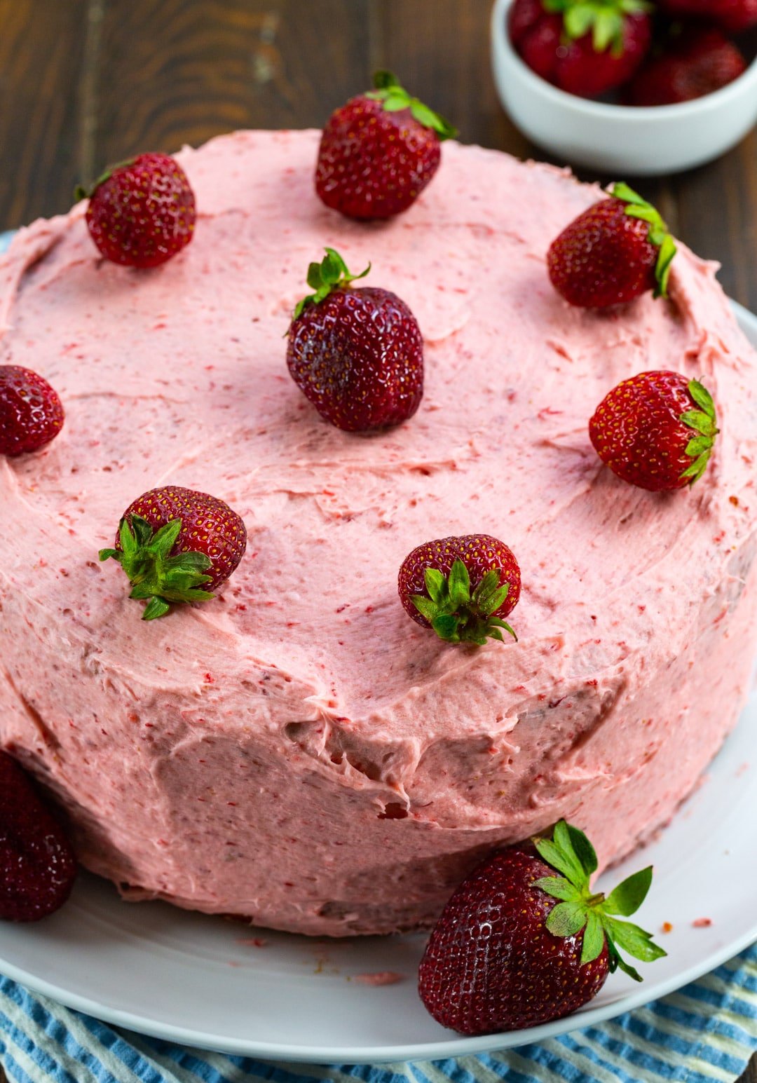 Whole strawberry cake decorated with fresh strawberries on a plate.