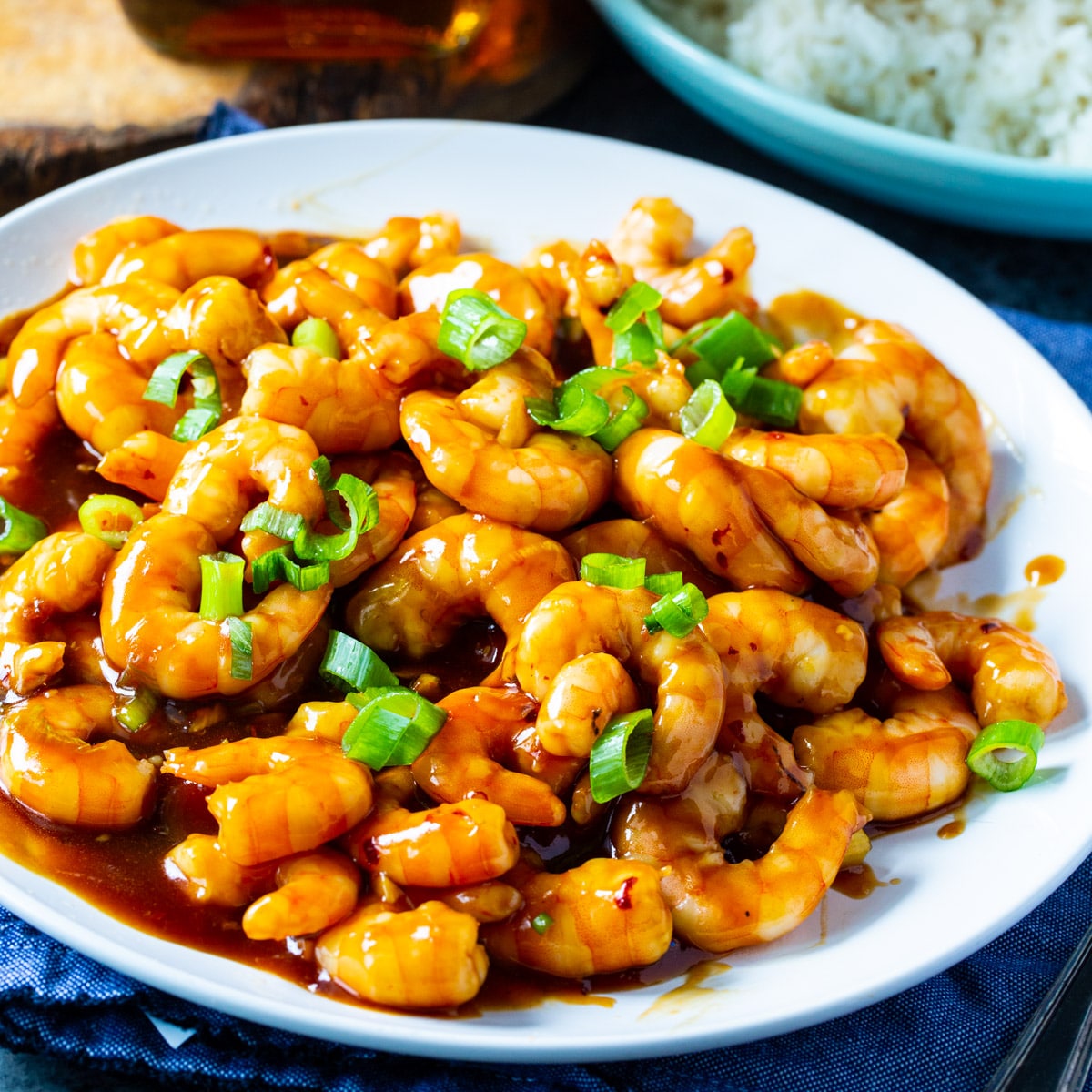 Bourbon Shrimp topped with sliced green onions on a plate.