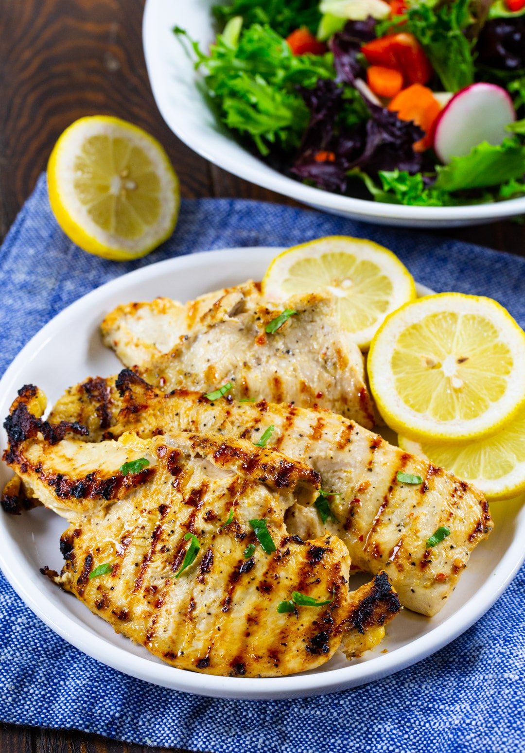Grilled chicken on a plate with lemon slices.