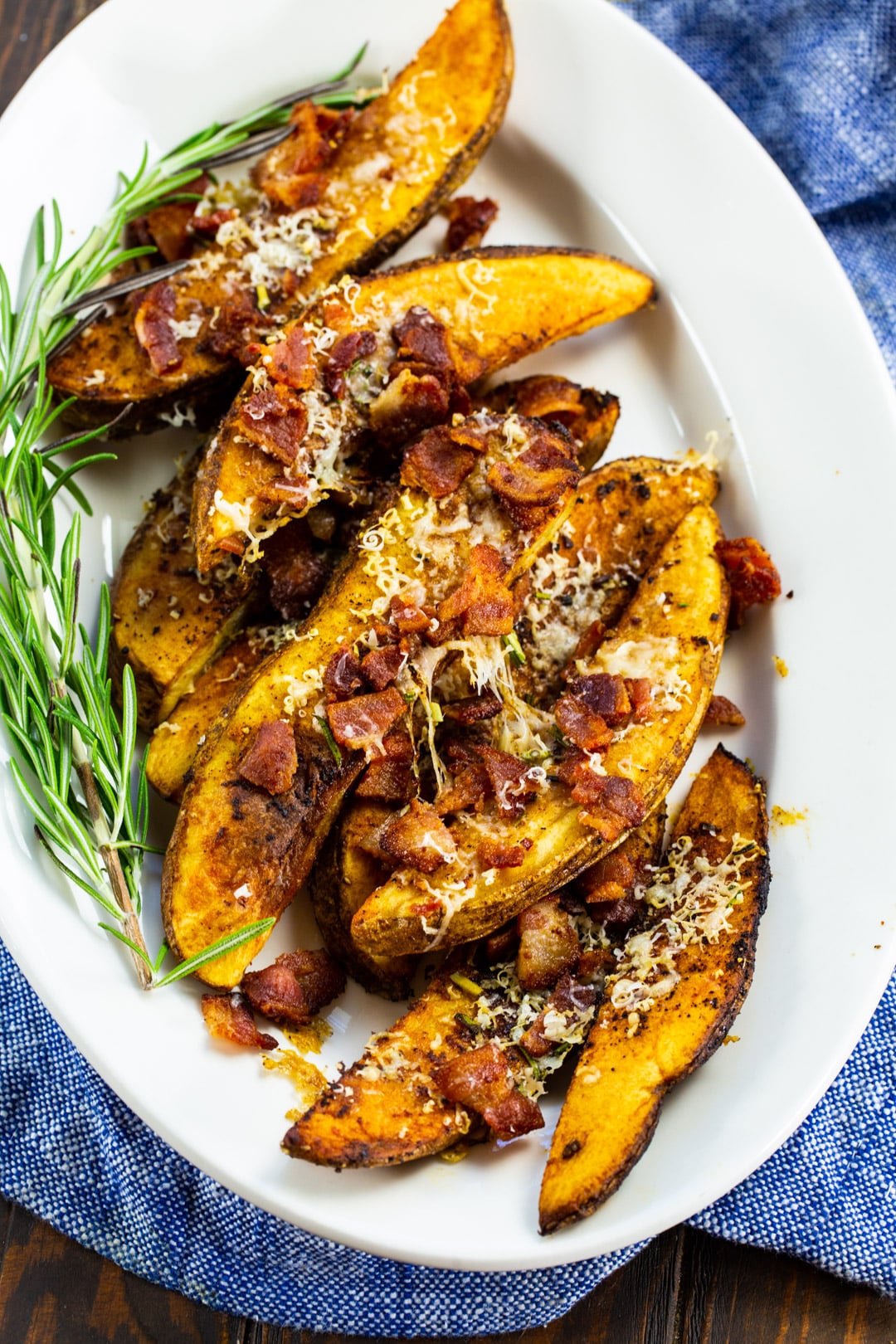 Bacon Parmesan Steak Fries on white platter with fresh rosemary.