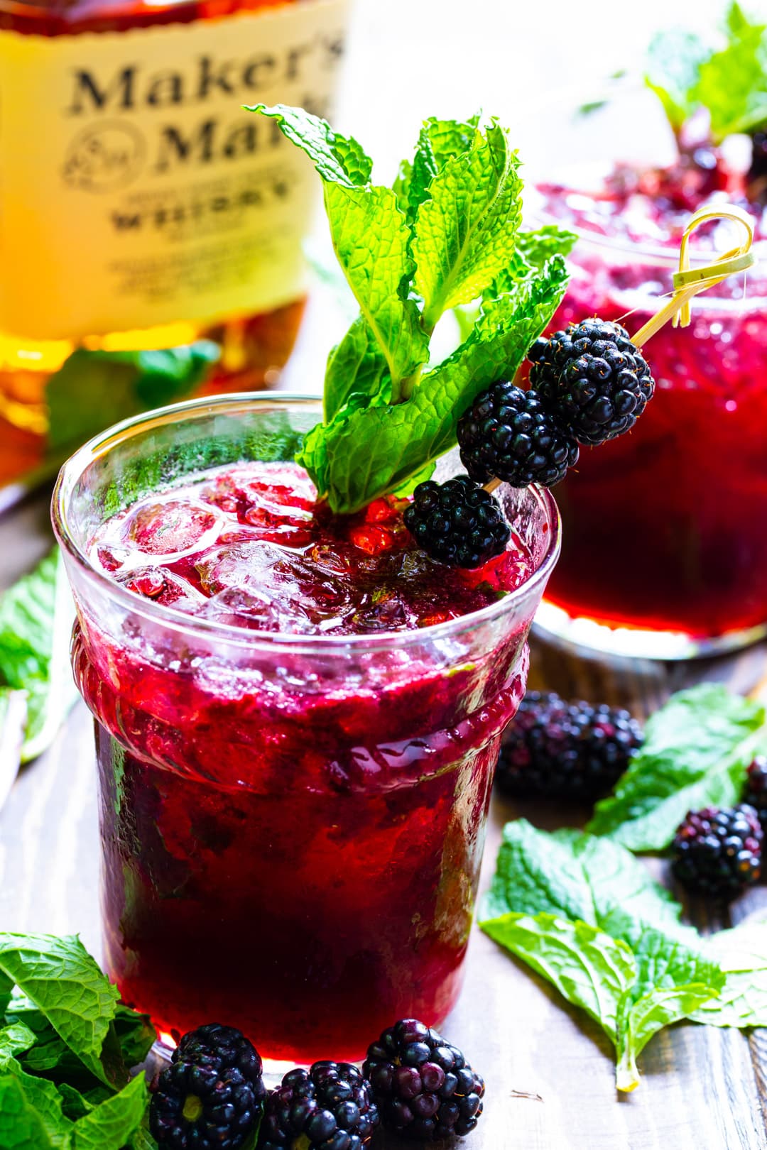 Blackberry Mint Julep in a glass surrounded by fresh mint and blackberries.