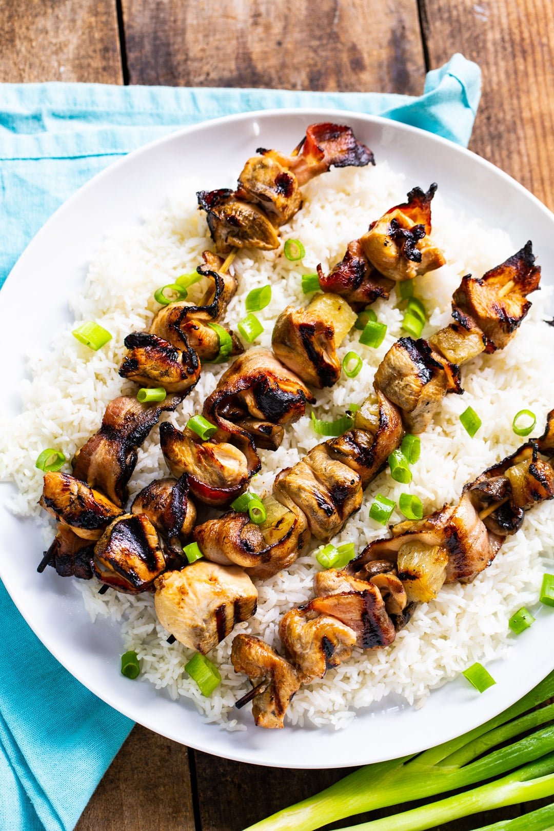 Four kabobs on a serving plate with white rice.