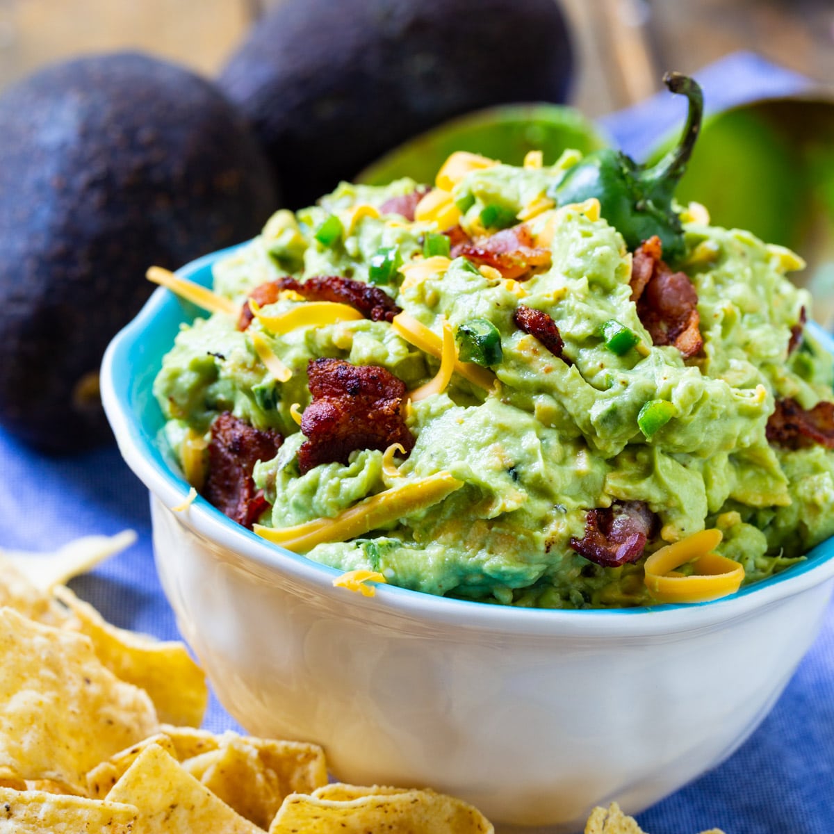 Jalapeno Popper Guacamole in a bowl surrounded by chips.