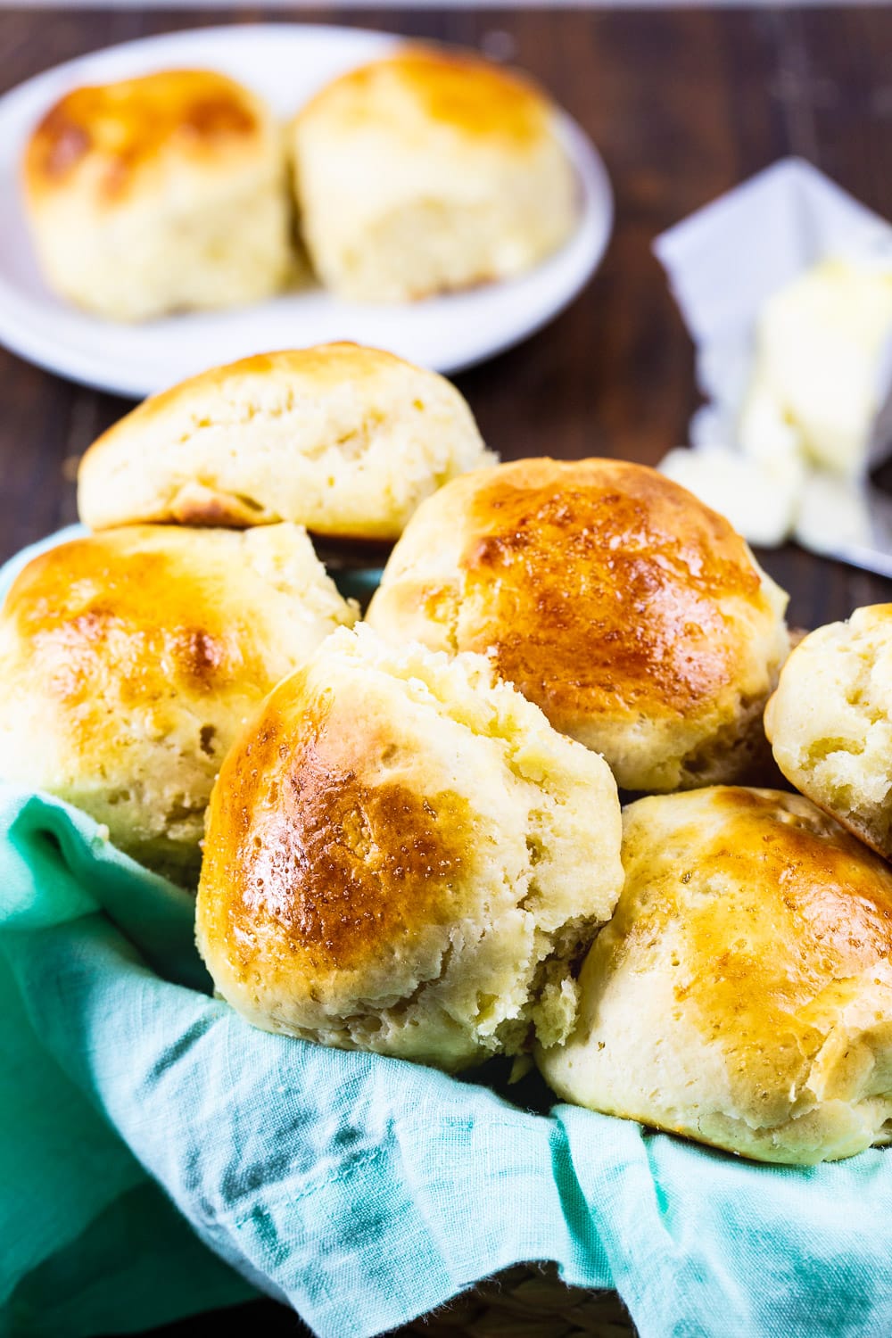 Rolls in a basket and 2 rolls on plate in background.