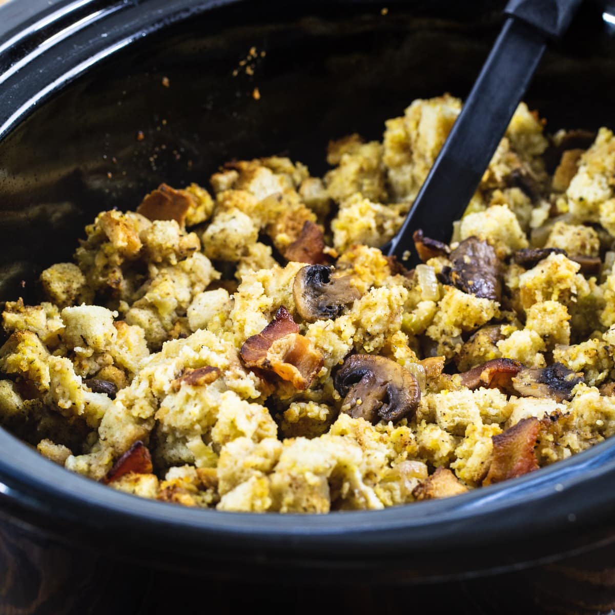 Slow Cooker Bacon Mushroom Dressing in a black slow cooker.