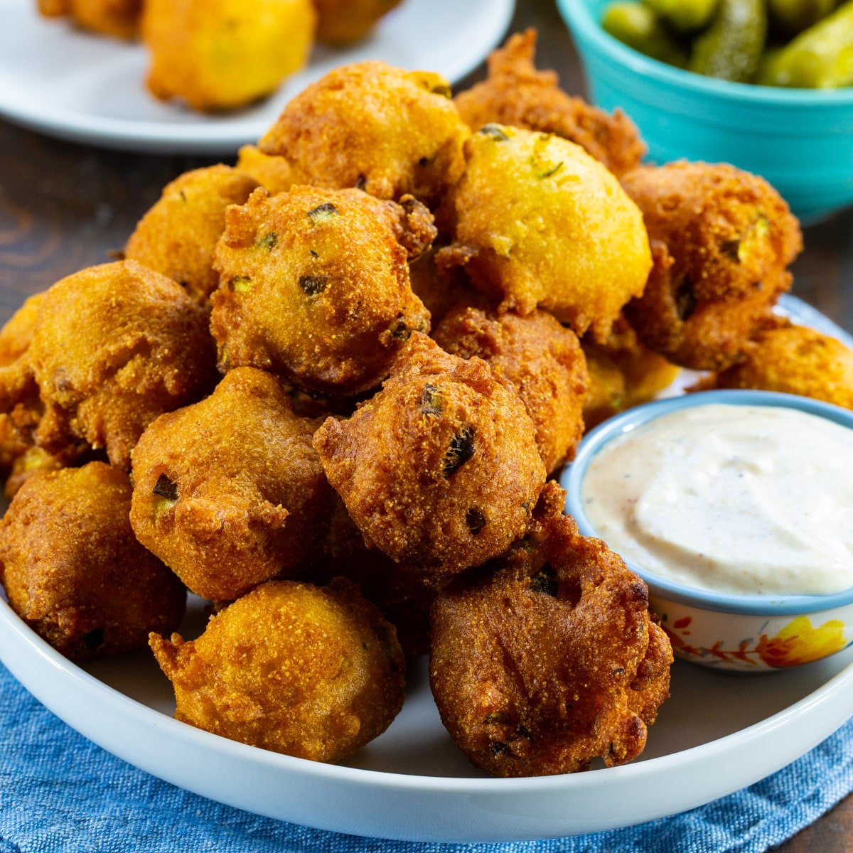 Spicy Pickle Hush Puppies on a plate with small bowl of white bbq sauce.