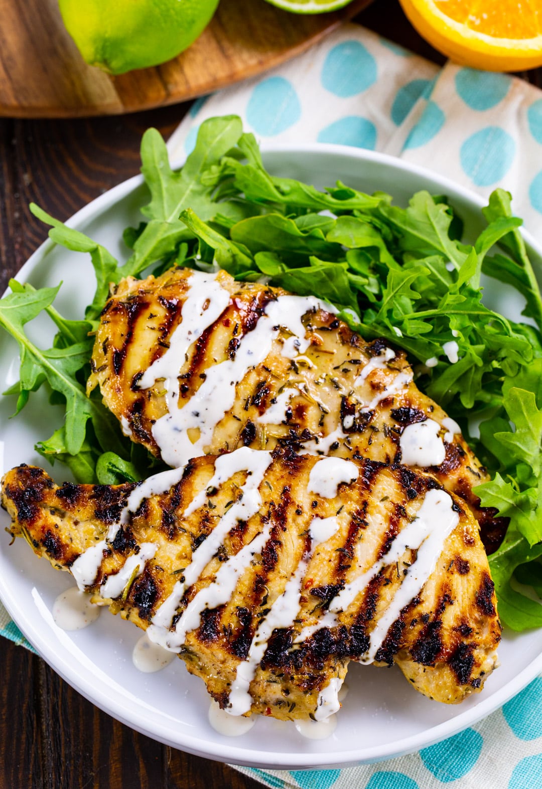 two Grilled Citrus Chicken Breasts on plate with arugula.