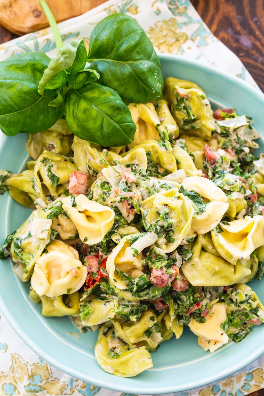 Creamy Spinach Tortellini in bowl with fresh basil.