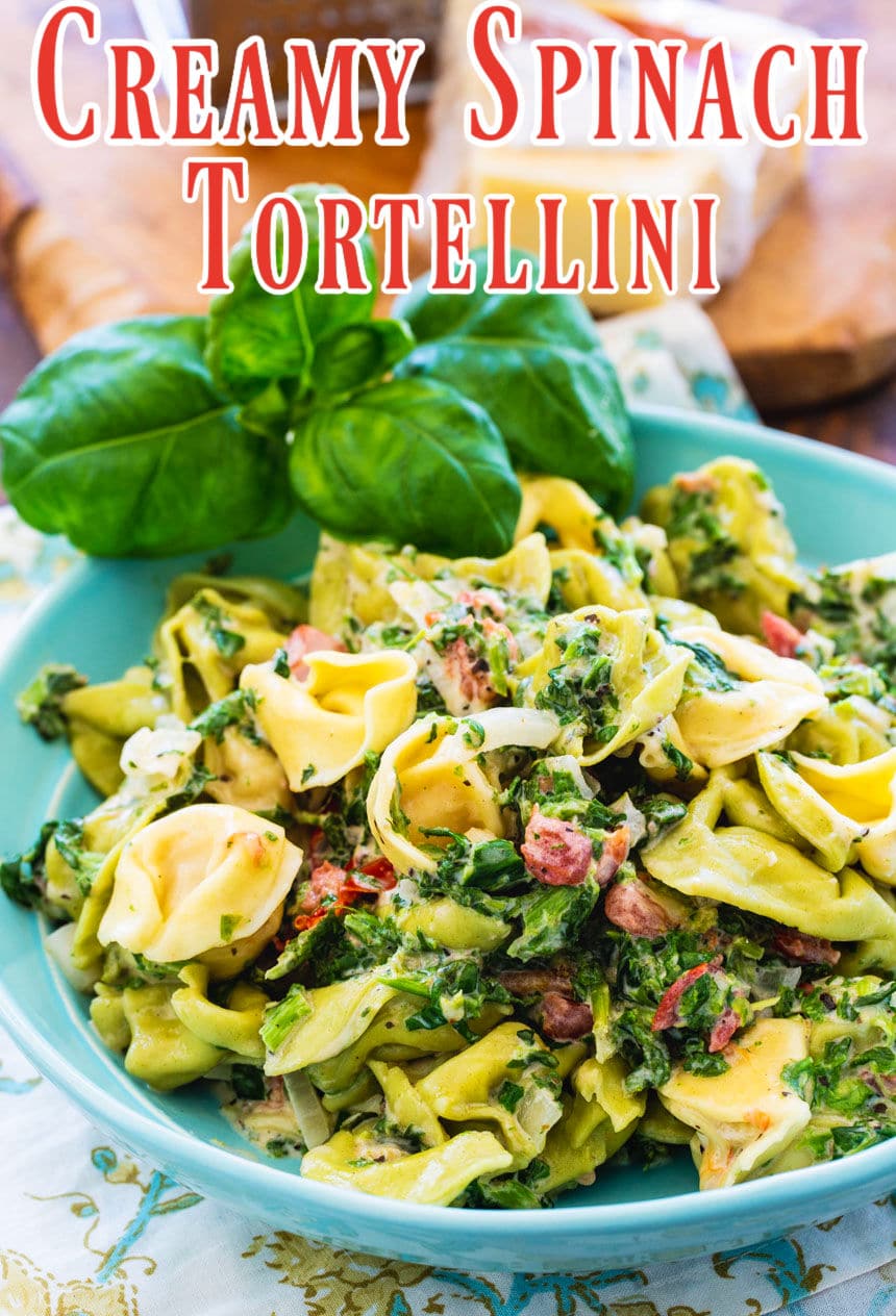 Tortellini with creamy spinach sauce in blue bowl.