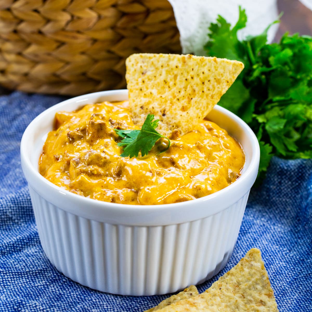 4-Ingredient Enchilada Dip in a white bowl with a chip stuck in the dip.