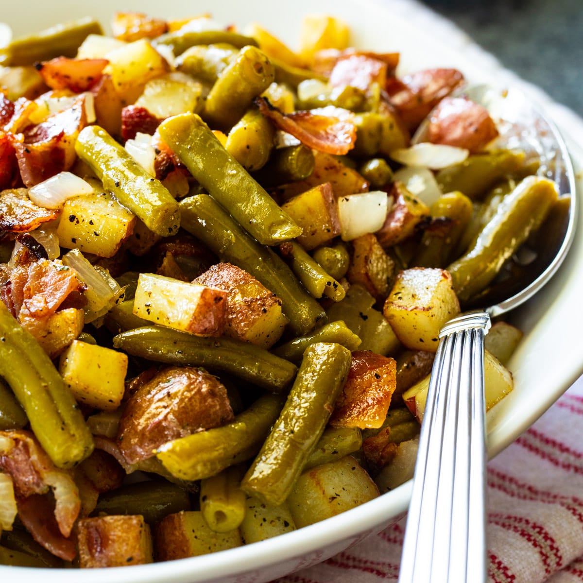 Country Ranch Green Beans and Potatoes in a serving bowl with spoon.