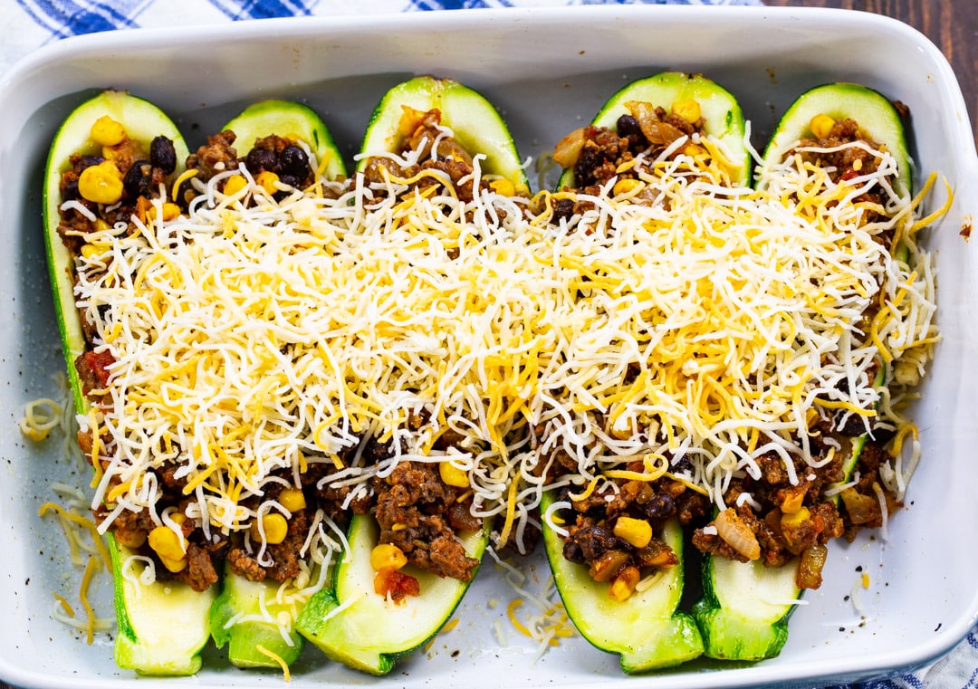 Cheese sprinkled on top of zucchini boats.