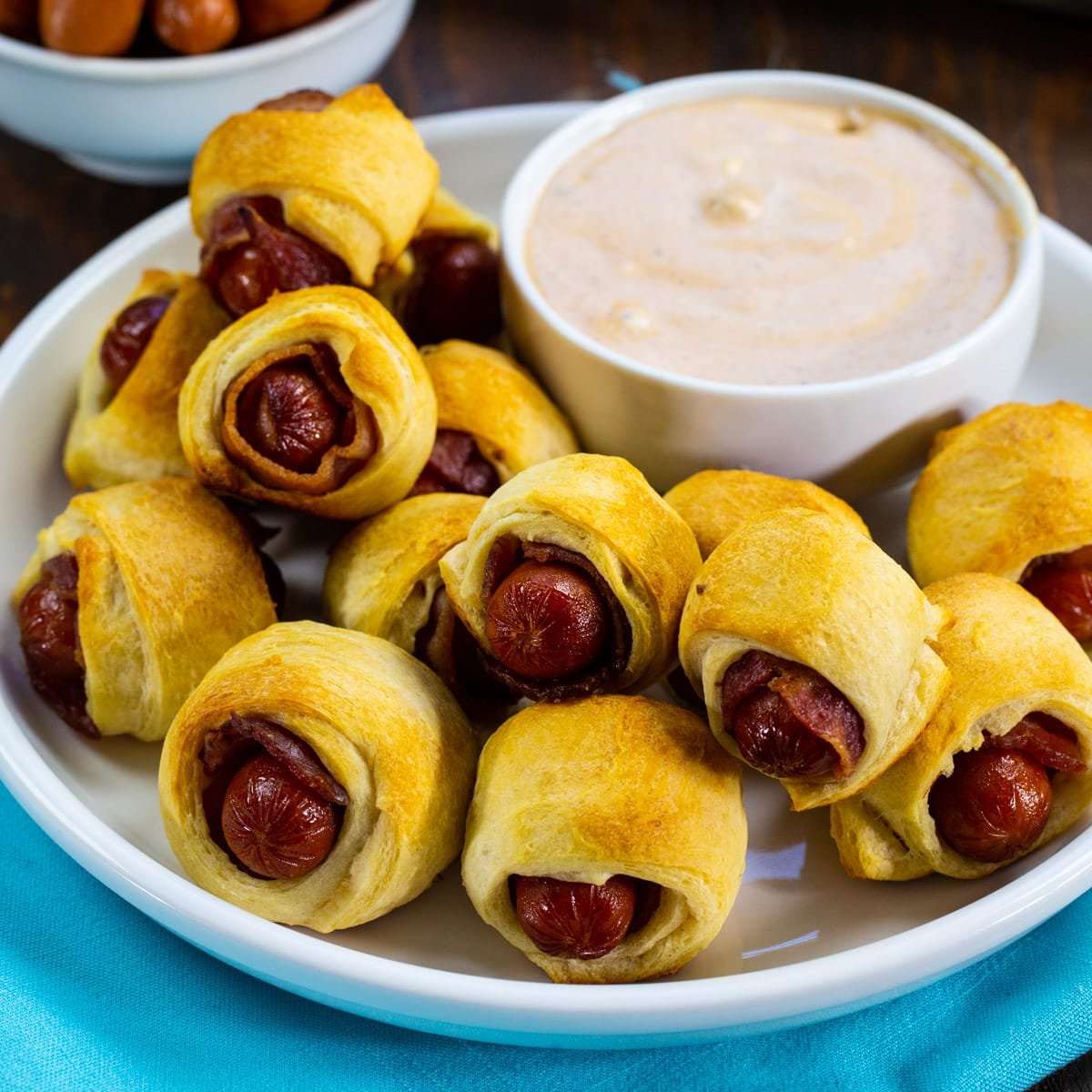 Bacon Pigs in a Blanket on a plate with bowl of BBQ Ranch.