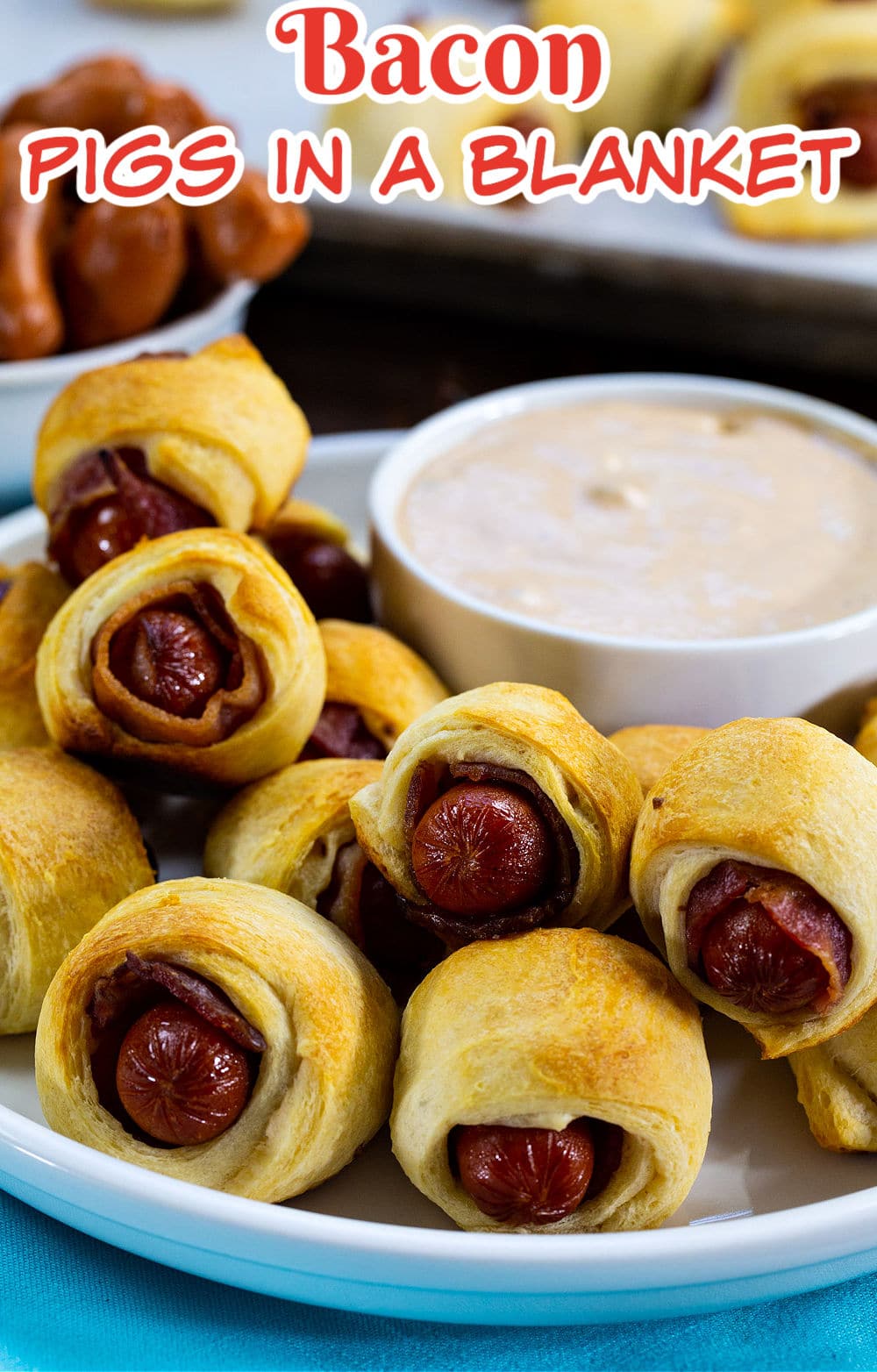 Bacon Pigs in a Blanket on a plate with bowl of dipping sauce.
