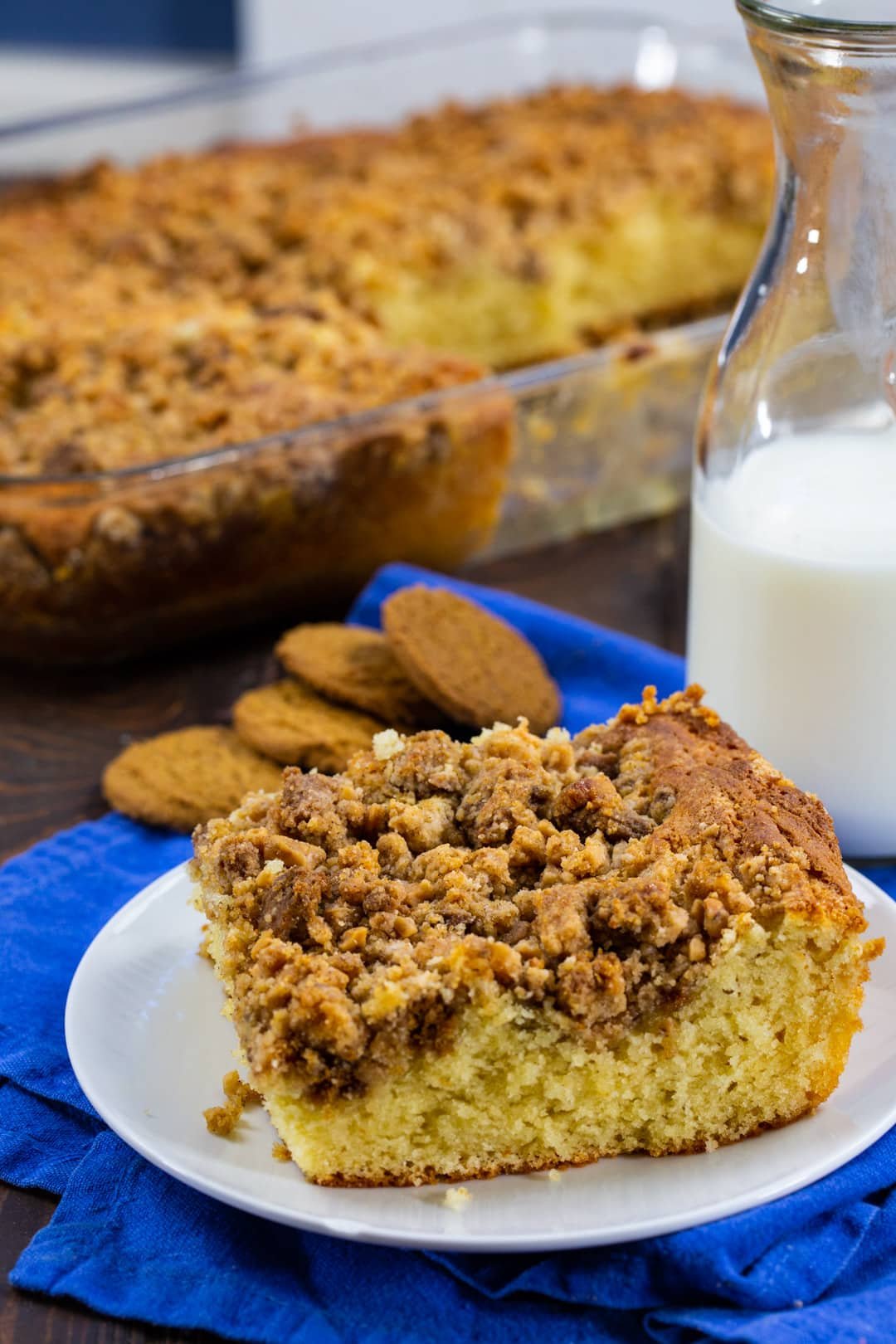 Piece of Coffee Cake on a plate with rest of coffee cake in background.
