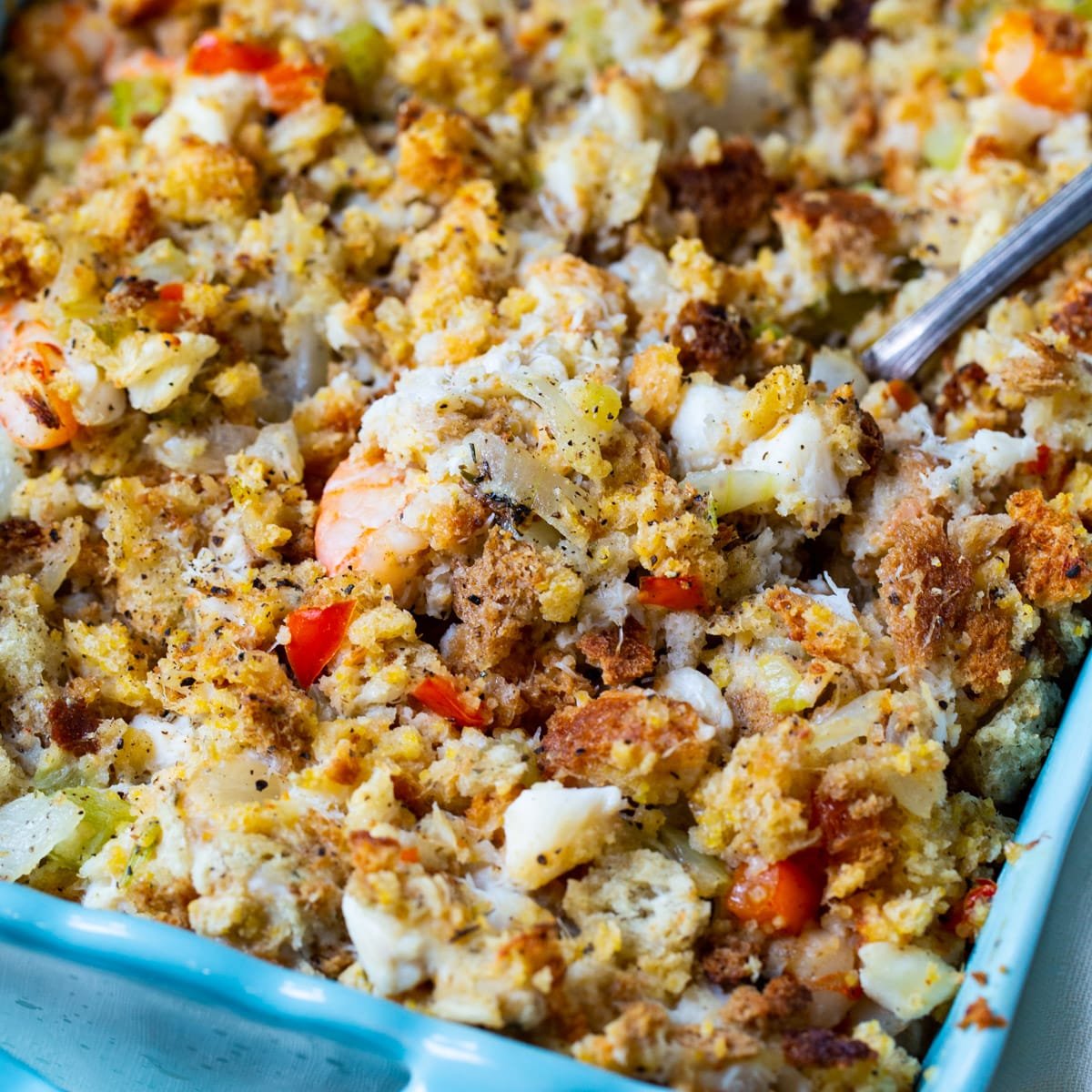 Spoon scooping stuffing out of baking dish.