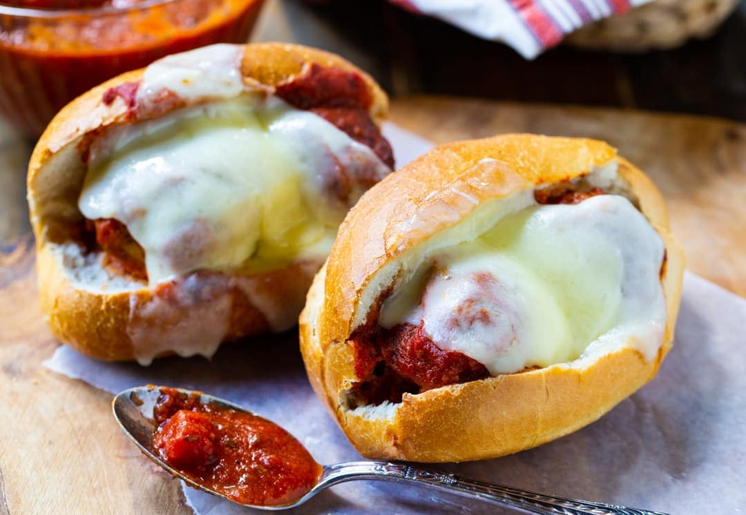 Two Slow Cooker Meatball Subs on a wooden board.