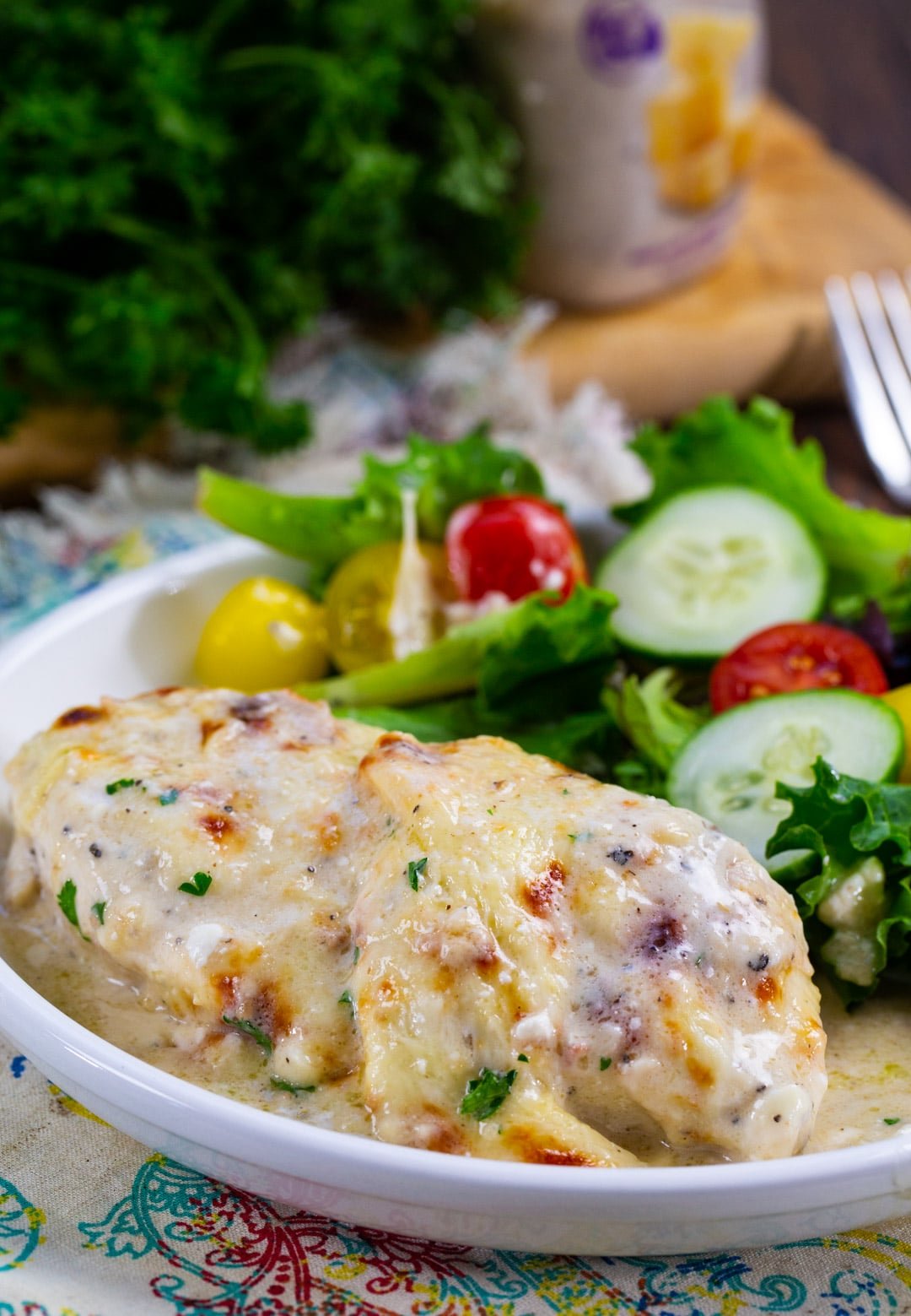 Baked Caesar Chicken on plate with salad.
