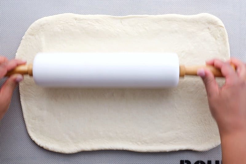 Rolling dough out with rolling pin.