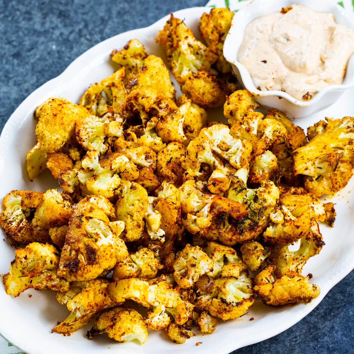 Cajun Roasted Cauliflower on a serving plate with bowl of remoulade.