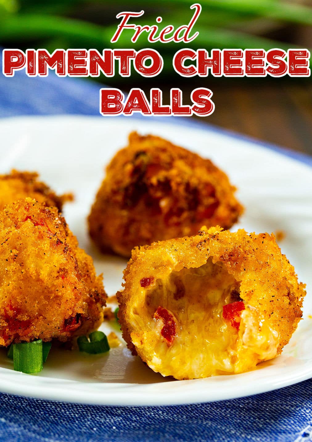 Fried Pimento Cheese Balls on a plate. One with a bite taken.