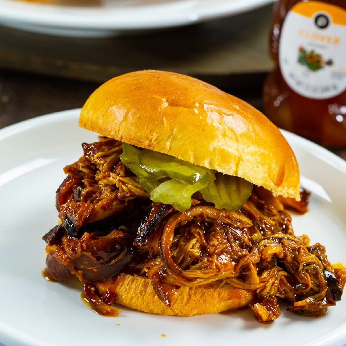 Slow Cooker Hot Honey Chicken on a bun with pickles.