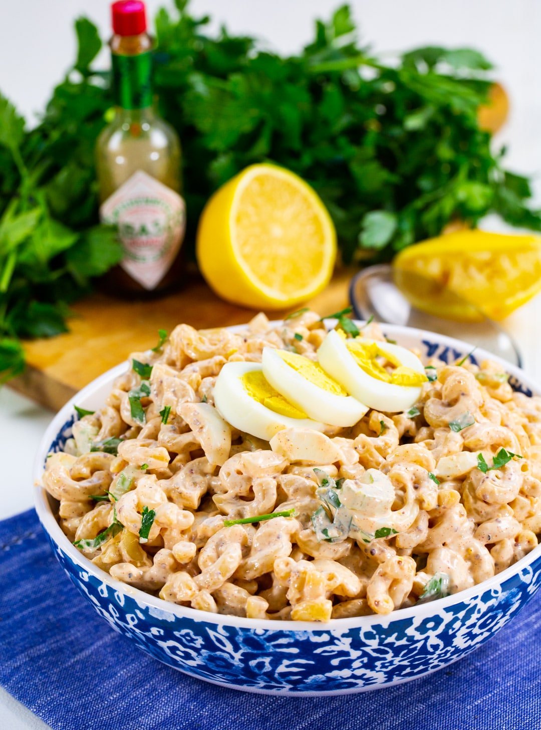 Cajun Macaroni Salad in serving bowl with parlsey and lemon in background.