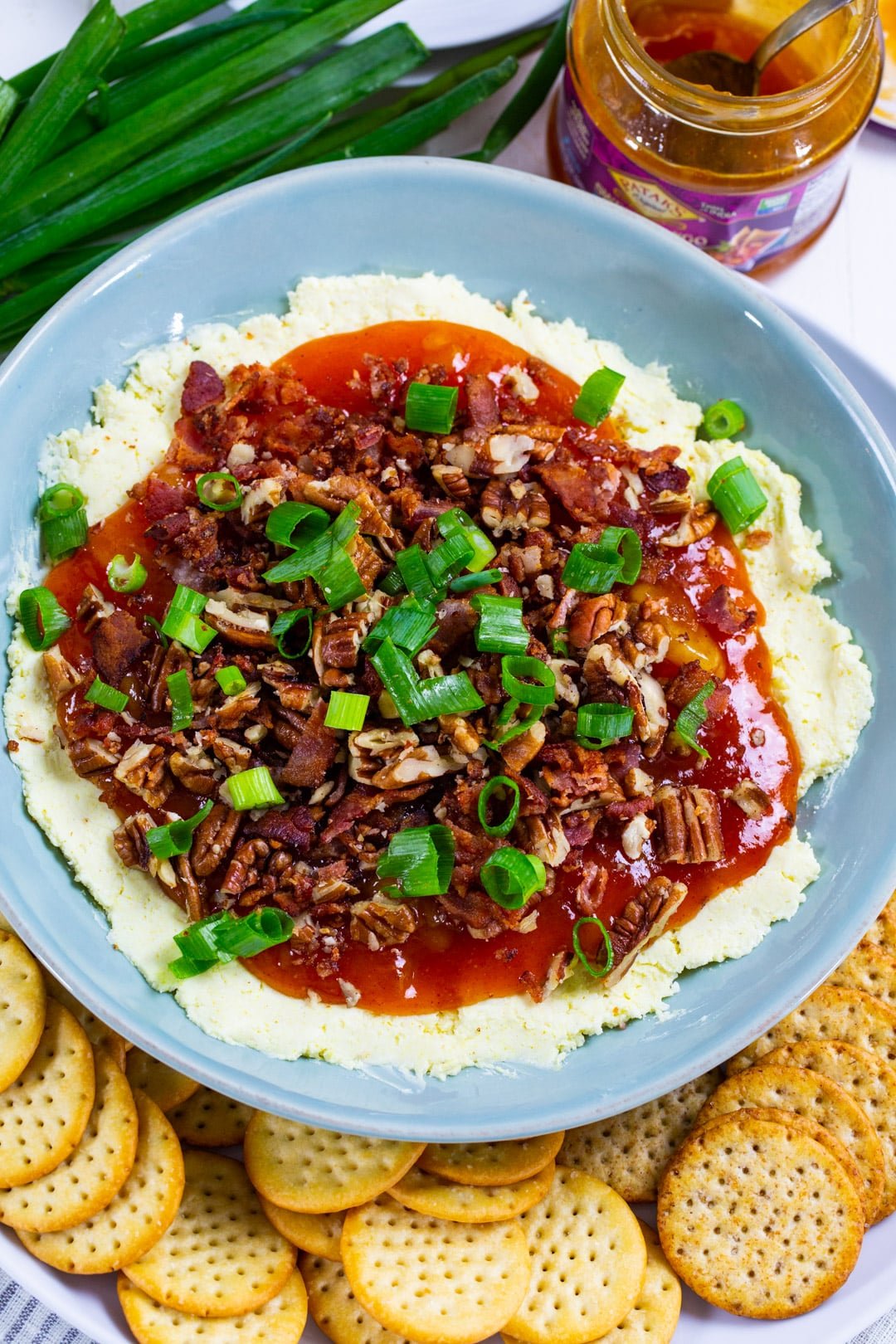 Cheese Dip topped with chutney in a bowl surrounded by crackers.
