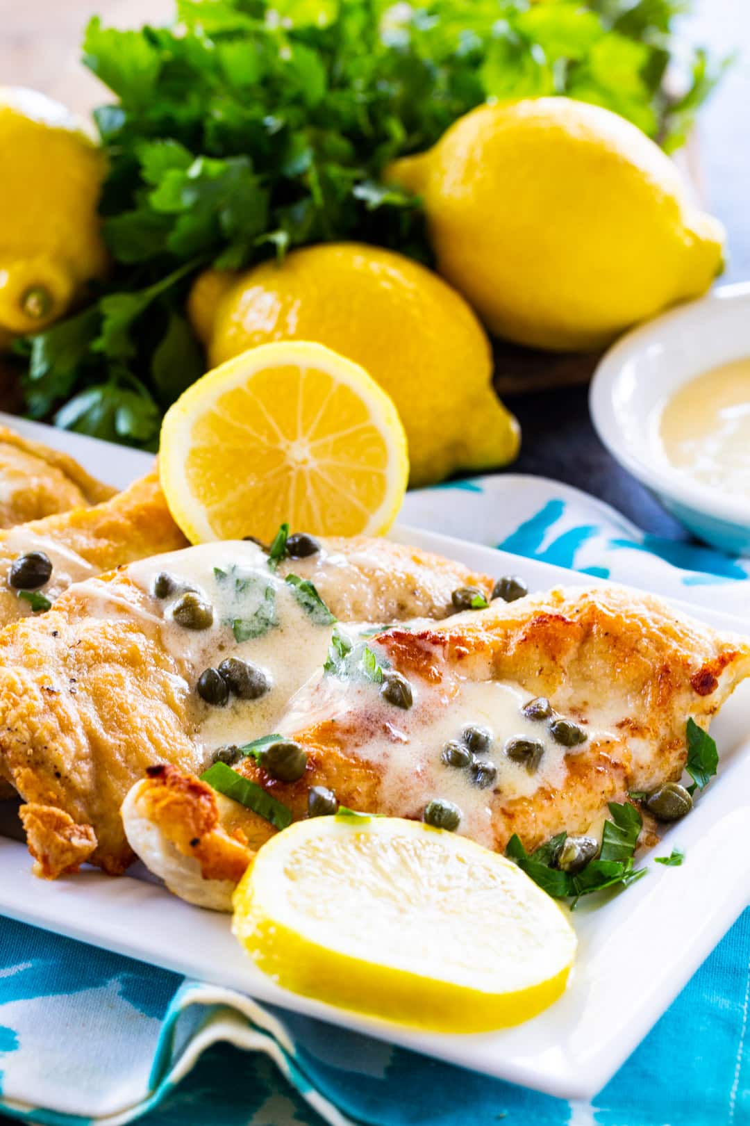 Chicken topped with lemon-caper sauce on a serving platter.