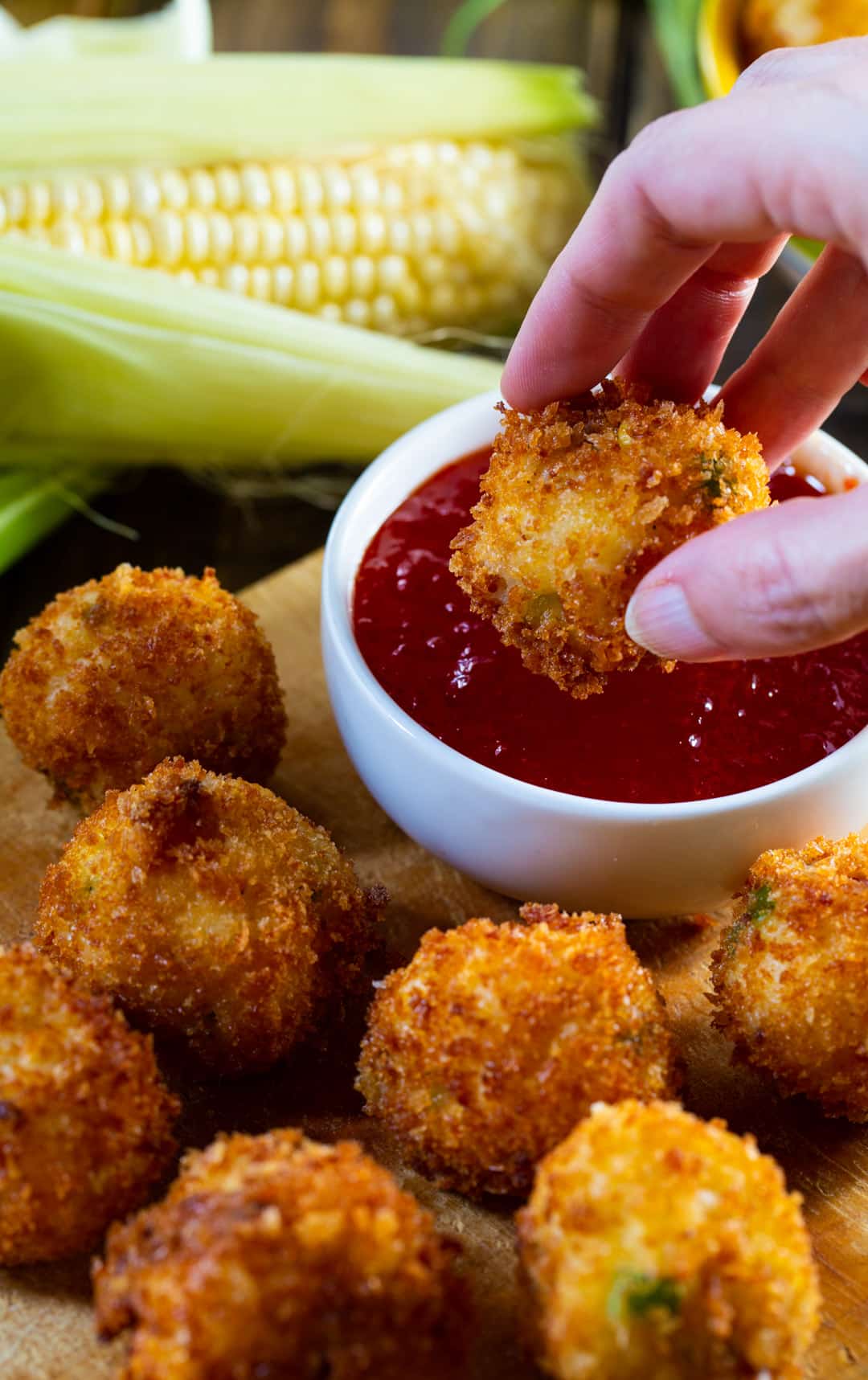 Hand dipping fritter in sauce.