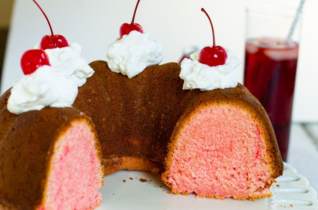 Cheerwine Bundt Cake topped with whipped cream and cherries.