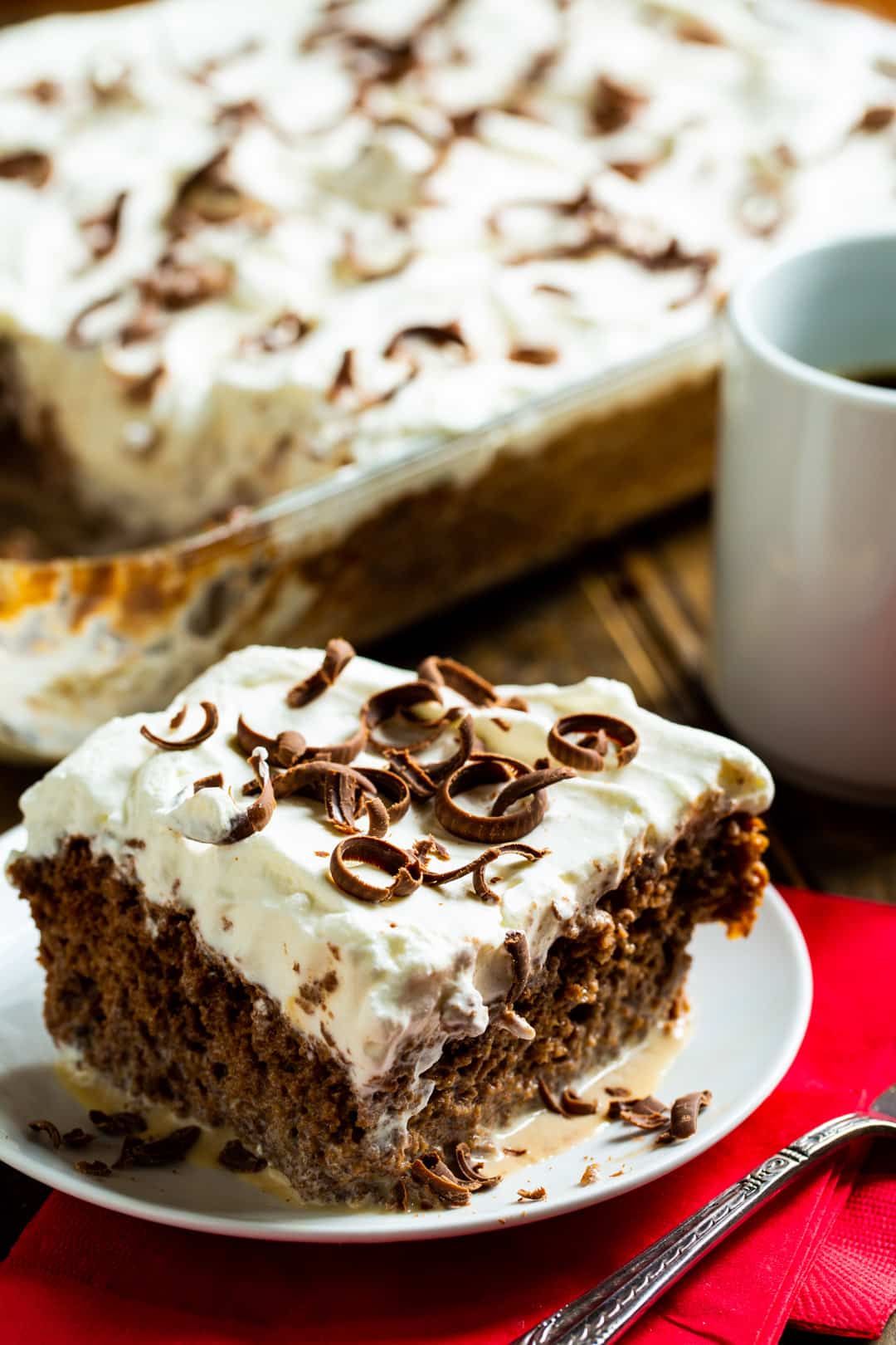 Slice of cake on a plate with rest of cake in background.