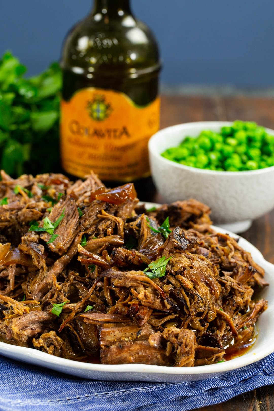Shredded Beef on serving plate and bowl of peas.