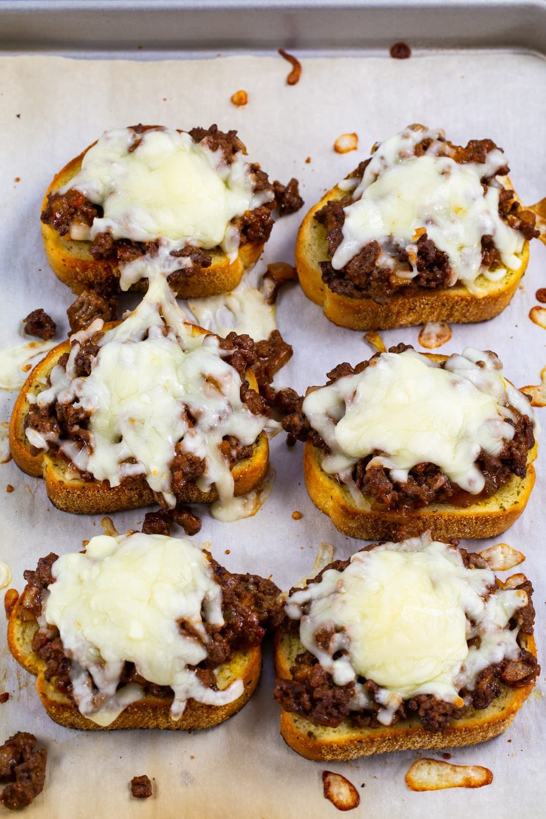 6 pieces Texas Toast covered with sloppy joe mixture on a baking sheet.