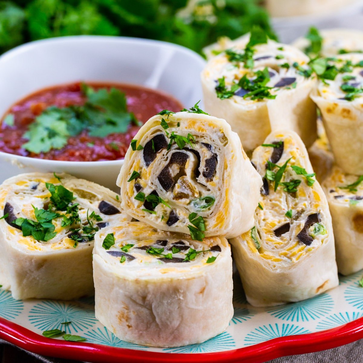 Tortilla Pinwheels on a plate with bowl of salsa.