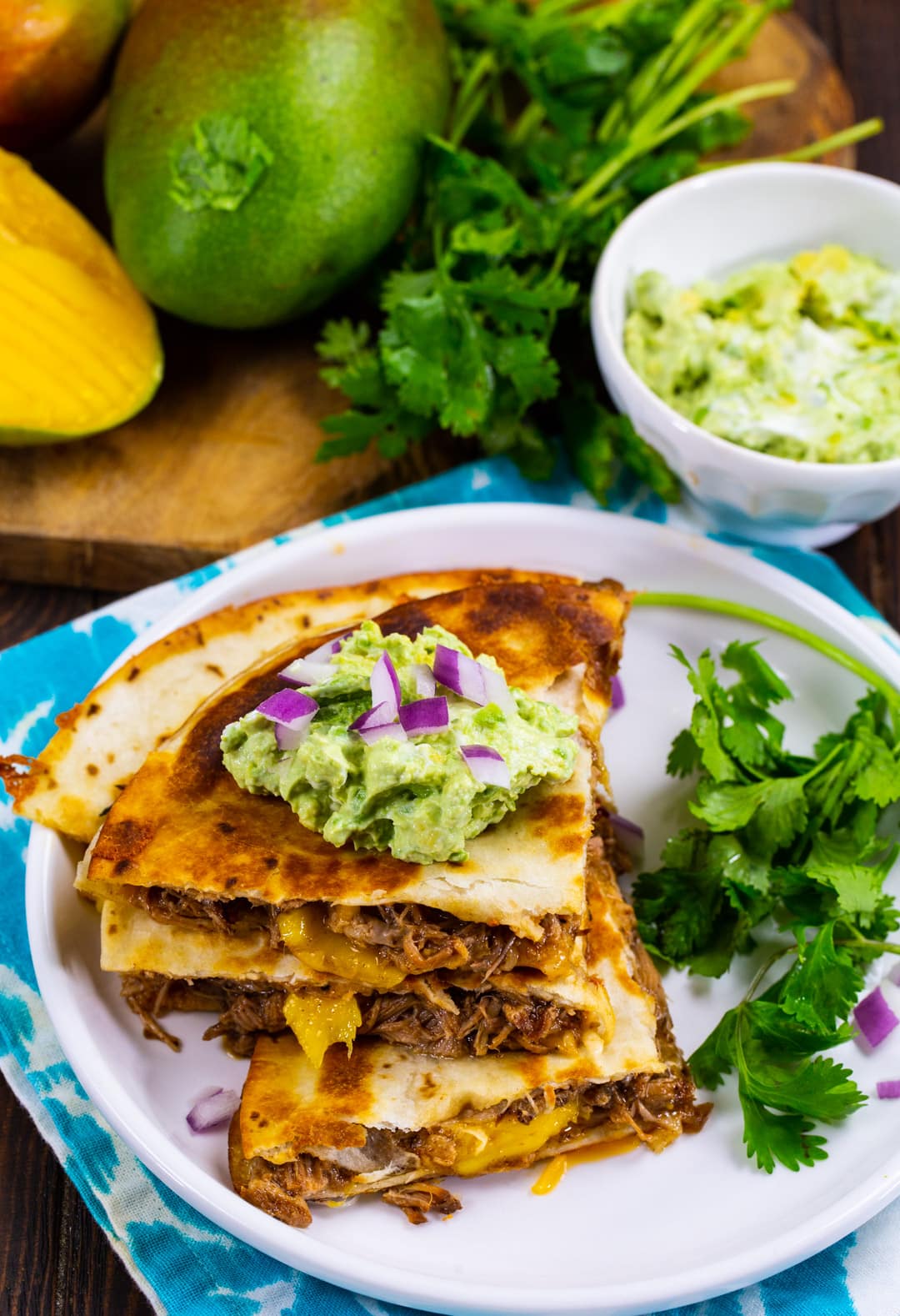 BBQ Pork and Mango Quesadilla triangles stacked up on a plate with fresh cilantro.