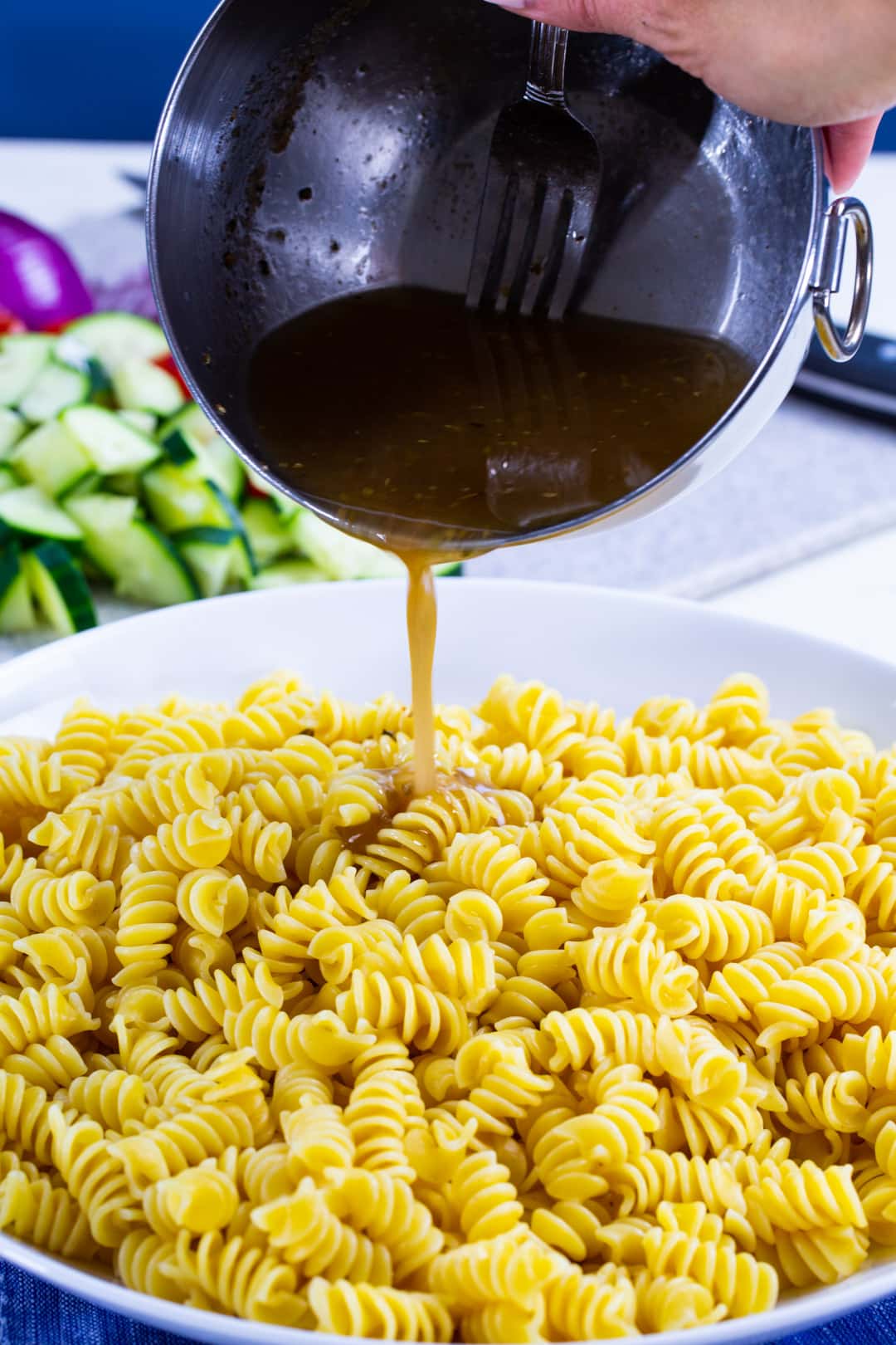 Dressing getting poured connected  pasta salad.