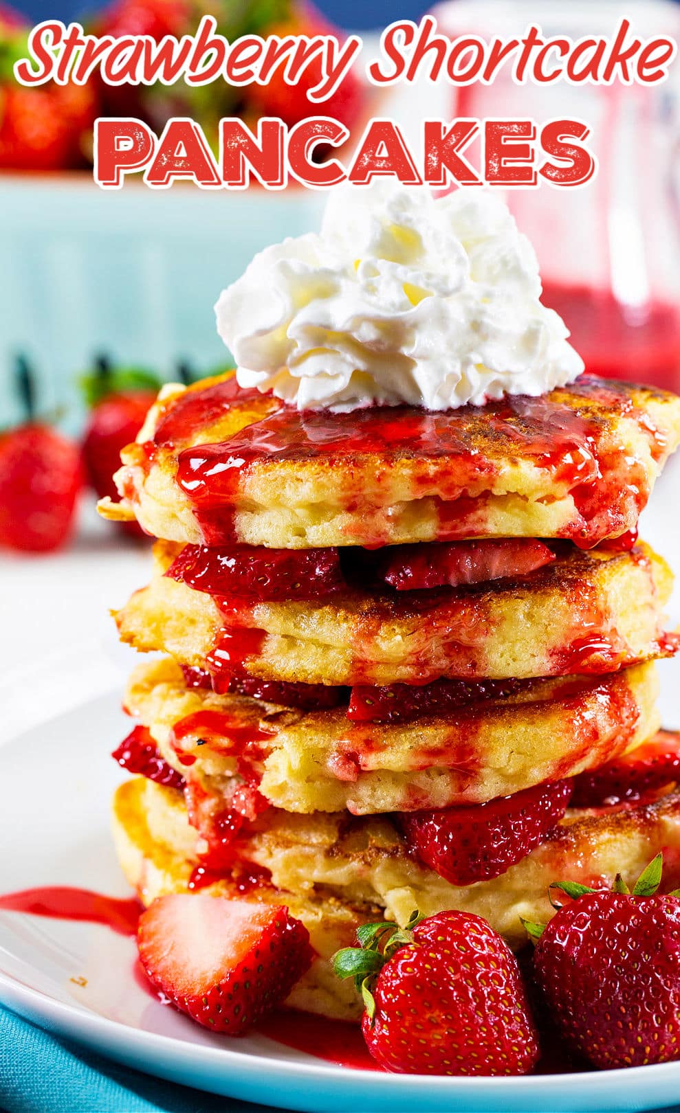 Stack of strawberry pancakes topped with whipped cream.