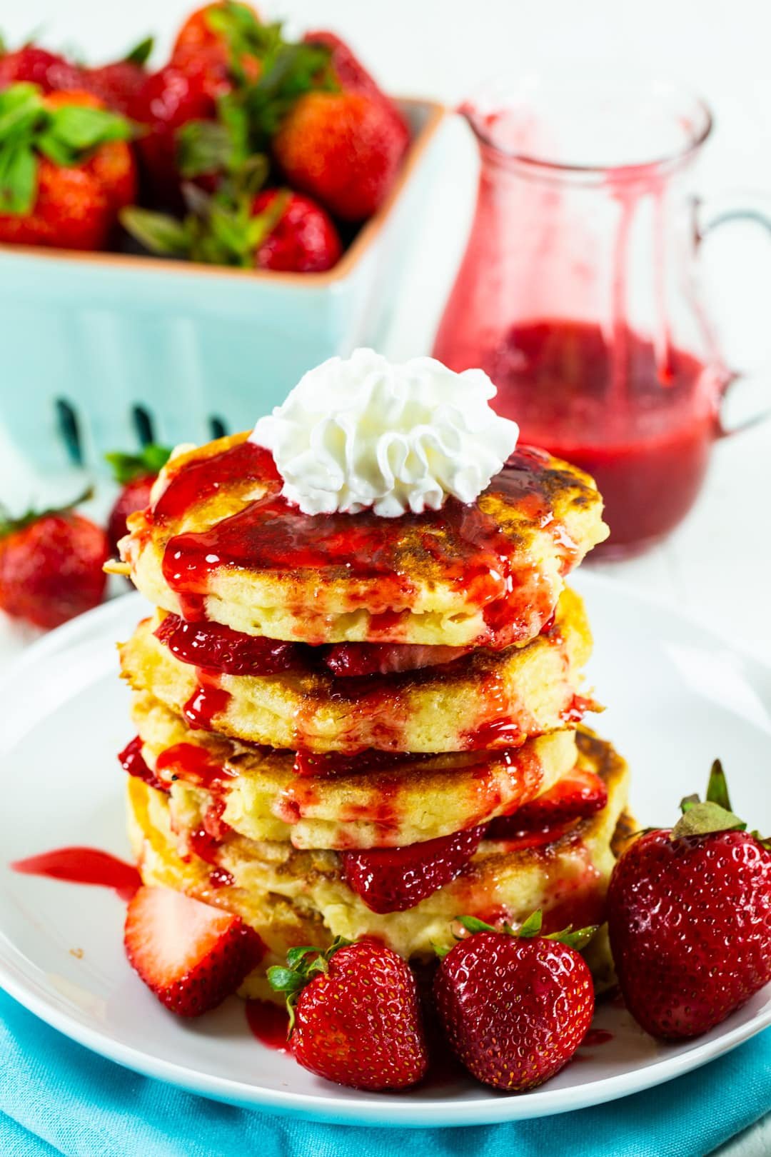 Stack of pancakes covered in strawberry syrup.